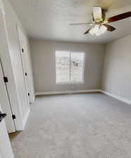 Carpeted spare room featuring ceiling fan and a textured ceiling