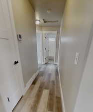 Corridor with a textured ceiling and light wood-type flooring