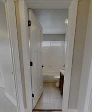 Full bathroom featuring shower / tub combination, tile patterned flooring, vanity, toilet, and a textured ceiling