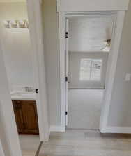 Corridor featuring sink, a textured ceiling, and light wood-type flooring