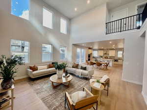 Living room with a high ceiling, light hardwood / wood-style floors, and plenty of natural light