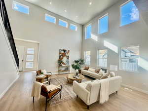 Living room featuring a towering ceiling and light hardwood / wood-style flooring