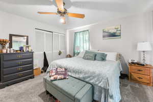 Carpeted bedroom with ceiling fan and a closet