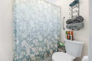 Bathroom with a shower with shower curtain and toilet