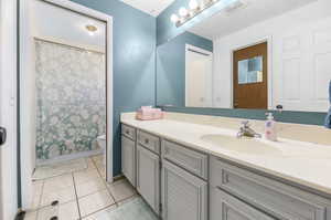 Bathroom with a textured ceiling, tile patterned flooring, vanity, toilet, and a shower with curtain