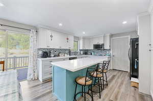 Kitchen with plenty of natural light, white cabinets, and light hardwood / wood-style flooring