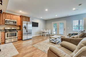 Basement interior space with living and dining area open to kitchen with stainless steel appliances, french doors.