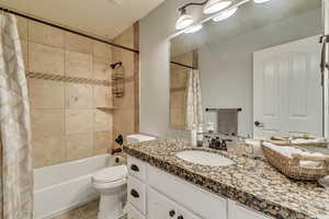 Full bathroom featuring tile patterned floors, shower / bath combo with shower curtain, vanity, and toilet.  Located off the 2nd floor hallway.