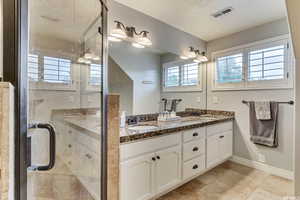 Ensuite bathroom featuring dual vanity sinks and travertine tile flooring.