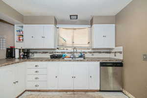 Kitchen with white cabinets, sink, backsplash, and dishwasher