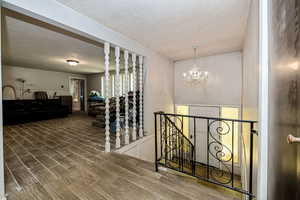 Hall featuring chandelier, a textured ceiling, and tile flooring