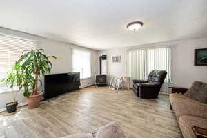 Living room with a textured ceiling, tile flooring, and a wood stove