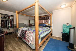 Bedroom with tile floors, ornamental molding, a textured ceiling, and a closet