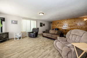 Living room featuring tile flooring, a wood stove, wooden walls, and a textured ceiling