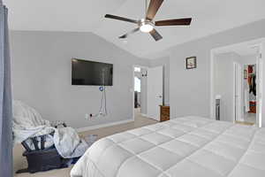 Primary Bedroom featuring light colored carpet, a walk in closet, vaulted ceiling, and ceiling fan