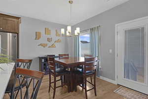 Dining area with hard surface flooring and a chandelier, door with internal blinds leading to backyard