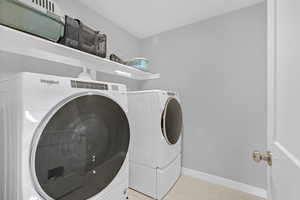 Laundry room with light tile patterned floors and separate washer and dryer