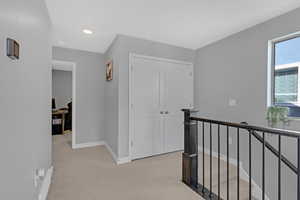 Corridor with light colored carpet and storage closet