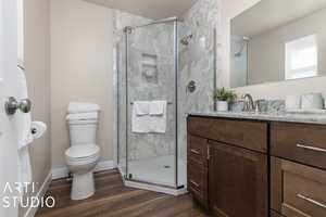 Bathroom with a shower with door, toilet, vanity, and hardwood / wood-style flooring