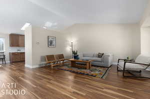 Living room with lofted ceiling with skylight and dark hardwood / wood-style flooring