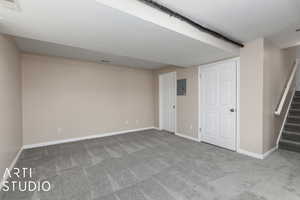 Basement featuring a textured ceiling, carpet floors, and electric panel