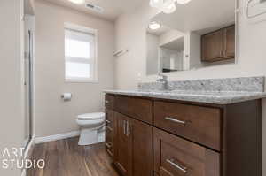 Bathroom featuring hardwood / wood-style flooring, a shower with door, toilet, and vanity