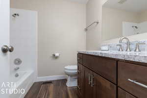 Full bathroom with hardwood / wood-style floors, tiled shower / bath combo, toilet, and vanity