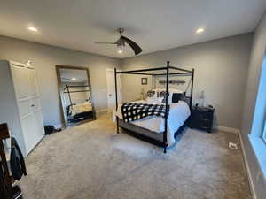 Carpeted bedroom with ceiling fan and a closet