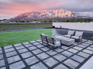 Patio terrace at dusk featuring a lawn and a mountain view