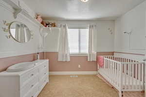 Bedroom with a crib and light carpet