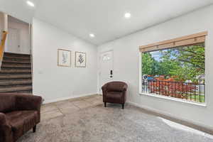 Living area with vaulted ceiling, light colored carpet, and a healthy amount of sunlight