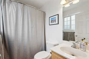 Bathroom with a shower with curtain, vanity, and toilet