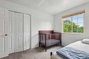 Carpeted bedroom featuring ceiling fan and a closet