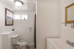 Bathroom featuring a shower with shower curtain, toilet, and vanity