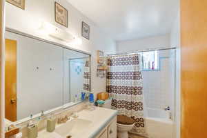 Full bathroom featuring vanity, shower / bathtub combination with curtain, and toilet