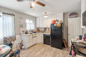 Kitchen featuring light hardwood / wood-style floors, white cabinets, ceiling fan, and black appliances