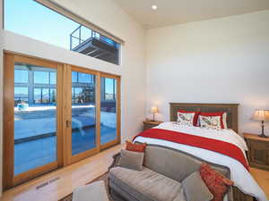 Bedroom featuring light wood-type flooring, a towering ceiling, and access to exterior