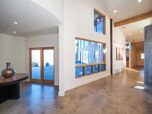 Interior space with vaulted ceiling with beams, concrete floors, and french doors