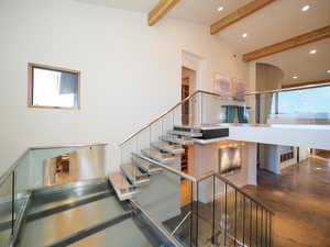 Stairway with high vaulted ceiling, beamed ceiling, and concrete flooring