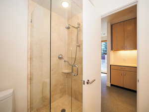 Bathroom with a shower with shower door, vanity, and toilet