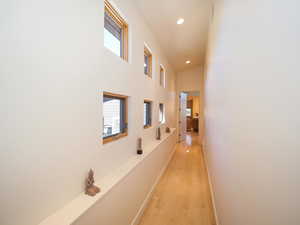 Hallway with a wealth of natural light, light hardwood / wood-style flooring, and a towering ceiling