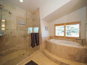 Bathroom with vaulted ceiling, tile patterned flooring, and separate shower and tub