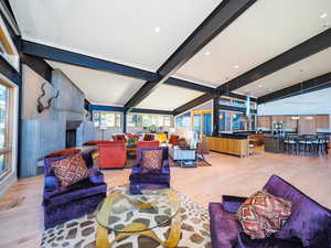 Living room with a wealth of natural light, light hardwood / wood-style floors, and lofted ceiling with beams