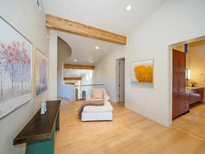 Bedroom with light hardwood / wood-style floors and lofted ceiling with beams