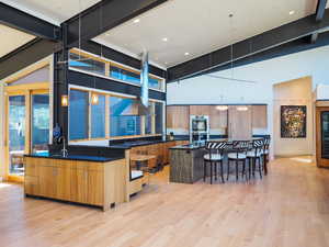 Kitchen with a breakfast bar, a center island, a high ceiling, light wood-type flooring, and double oven