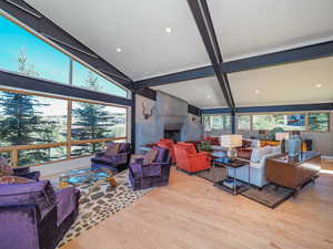 Living room featuring a fireplace, vaulted ceiling with beams, and light wood-type flooring