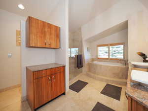 Bathroom with tile patterned floors, vaulted ceiling, and vanity