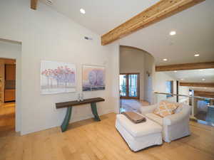 Living room featuring light wood-type flooring, beam ceiling, and high vaulted ceiling