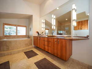 Bathroom featuring dual vanity, a relaxing tiled tub, tile patterned floors, and a healthy amount of sunlight