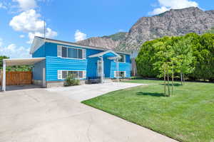 View of front of home with a carport, a mountain view, and a front yard